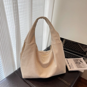 Détail macro du sac hobo en velours côtelé crème avec texture rayée et bandoulière