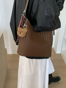 Minimalist deep brown woven bucket bag with long shoulder strap and cute bear charm