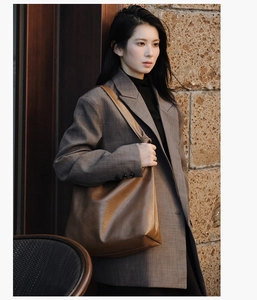 Detail of soft brown leather tote bag with shoulder knot and smooth glossy finish
