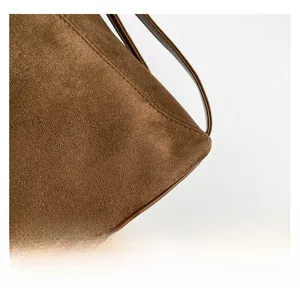 Detailed close-up of brown suede fabric with precise stitching on a minimalist backpack