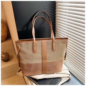 Close-up of contrast woven canvas tote bag with brown leather handles and side drawstrings