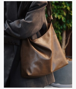 Detail of a large brown vintage leather tote bag with stylish knot strap on a model shoulder