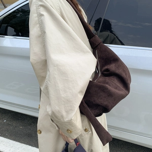 Detail of dark brown suede crescent hobo bag with knotted strap on beige trench coat