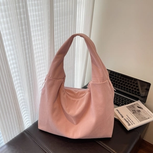 Sac fourre-tout en velours rose avec forme en demi-lune sur une surface noire lisse