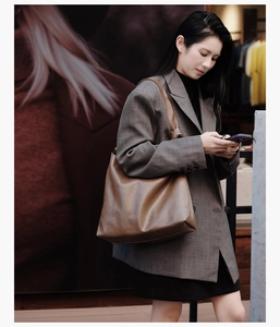 Detailed texture of a brown soft leather tote bag worn by a model in a commute setting