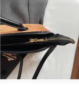 Détail de la fermeture éclair dorée sur un sac cabas en daim marron et cuir noir