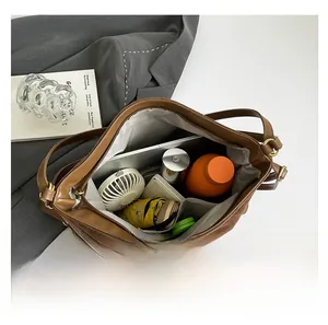 Macro view showing the large capacity interior of the brown matte tote bag with daily items