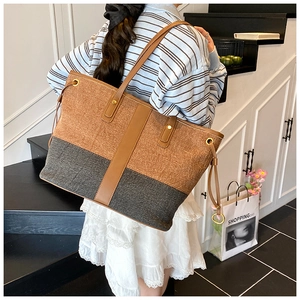 Detail of a large canvas tote bag with ginger and grey patchwork and brown leather straps