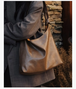 Detail of dark brown hobo bag featuring knotted shoulder strap and glossy crinkled texture