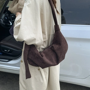 Deep coffee suede dumpling bag shown on model with beige trench coat for size reference