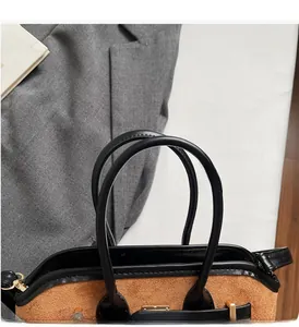 Détail des poignées renforcées en daim marron et du fermoir en métal doré du sac à main