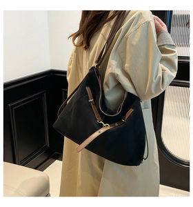 Side view of large black suede tote bag styled with a beige trench coat in a minimalist studio