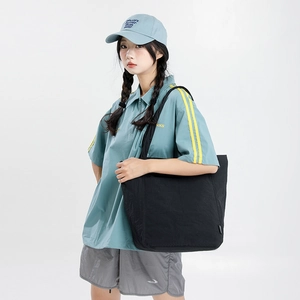 Sac fourre-tout noir minimaliste porté avec une tenue de sport décontractée pour le quotidien