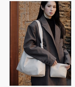 Close-up of off-white leather tote and matching pouch with premium soft texture details