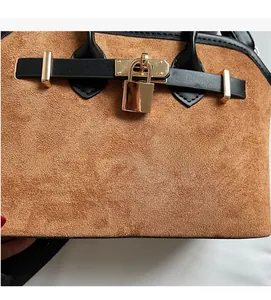 Détail de la matière en daim marron avec sangle en cuir noir et fermoir en métal doré