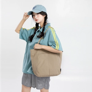 Détail d'un grand sac cabas kaki en nylon avec poche externe présenté en mode lifestyle