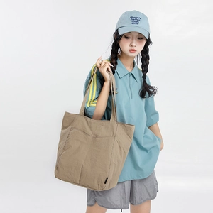Gros plan du sac cabas en nylon marron clair montrant la poche avant et la texture du tissu