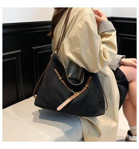Detailed view of a black canvas tote with brown leather straps worn with a beige trench coat