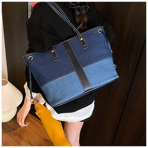 Detail of denim patchwork tote bag with contrast stitching and leather handles