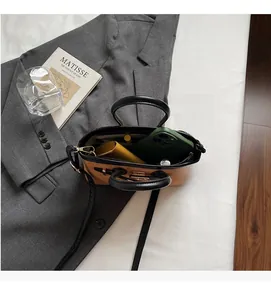 Vue de dessus montrant l'intérieur spacieux du sac marron bicolore avec objets quotidiens