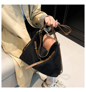 Detail of adjustable brown leather strap with gold buckle on black suede tote bag