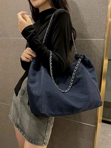 Large dark blue denim tote bag with silver chain strap shown on a model for daily style
