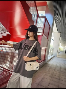 Street style view of a white utility crossbody bag with functional drawstring and buckle