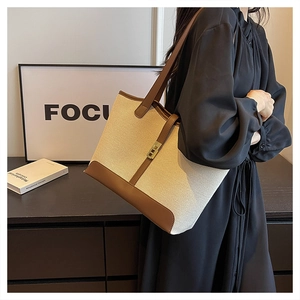 Detail of canvas tote bag with brown leather trim and golden buckle for women