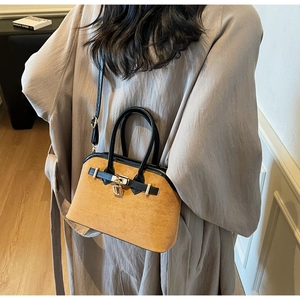 Détail du sac à main trapèze en daim marron avec poignée noire et cadenas doré