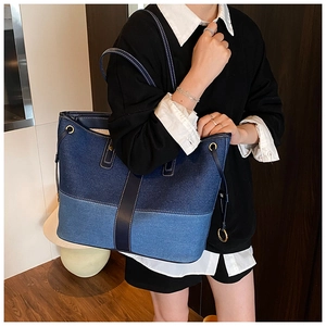 Detail of blue denim patchwork tote bag with leather strap and gold ring hardware