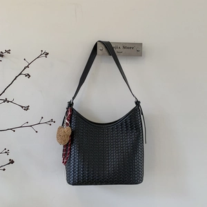 Détail du sac seau hobo tissé main noir avec breloque ours en peluche et ruban rayé