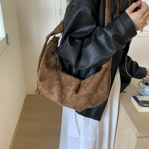 Detail of a brown suede hobo bag featuring a side zipper and decorative knot strap design