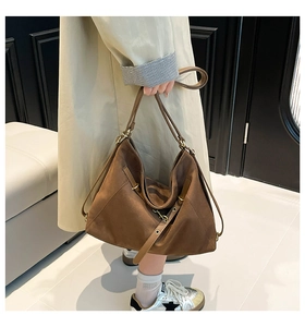 Detail of large brown suede tote bag featuring adjustable brass hardware and long handles