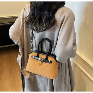 Détail du sac en daim camel avec poignées en cuir noir et cadenas doré décoratif