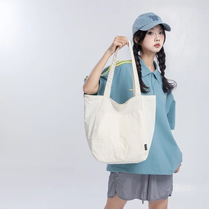 Vue détaillée du grand sac fourre-tout en nylon crème avec poches avant et texture fine