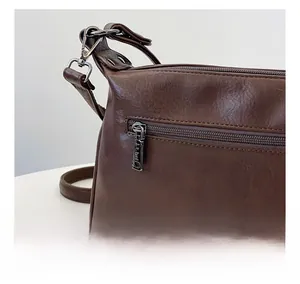 Detailed back view of a retro brown leather bag featuring a smooth silver metal zipper pocket