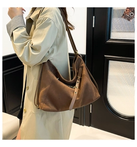 Brown suede hobo tote bag worn by model in a minimalist stylish indoor setting