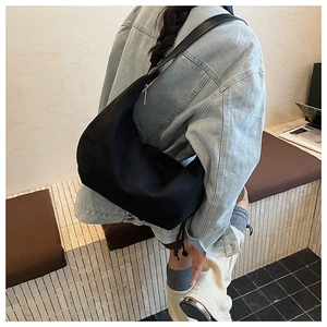Detail of a black large-capacity shoulder bag with soft matte texture and drawstring accents