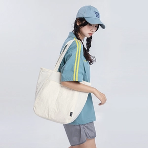 Gros plan d'un grand sac cabas en toile crème montrant sa capacité et son logo latéral
