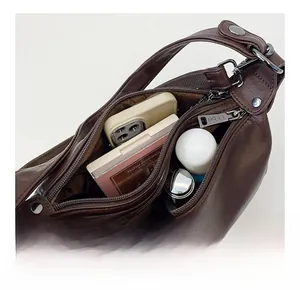 Internal capacity of dark brown leather shoulder bag showing phone and cosmetics
