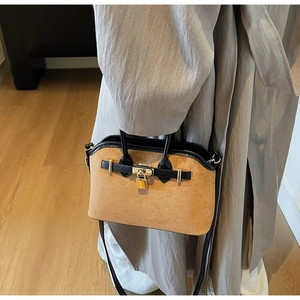 Détail du sac en daim contrasté avec cadenas doré et poignée en cuir de qualité