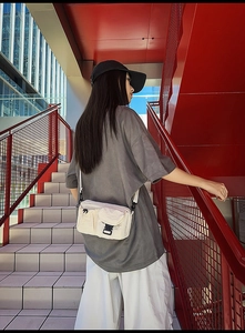 Detail of off-white nylon crossbody bag featuring black buckle and drawstring detail