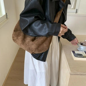 Brown suede slouchy crescent bag shown with casual outfit in minimalist interior