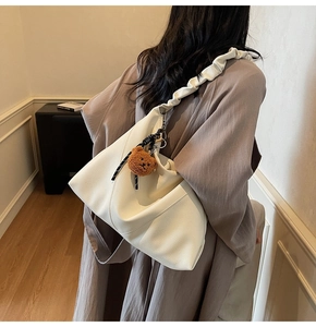 Détail d'un sac cabas en cuir crème avec texture litchi et bandoulière à plis élégants