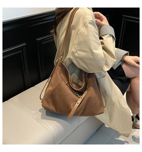 Detail view of large brown suede tote bag with adjustable leather strap and metal eyelets