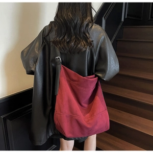 Detail of burgundy canvas hobo bag with black leather strap and metal buckle adjustment
