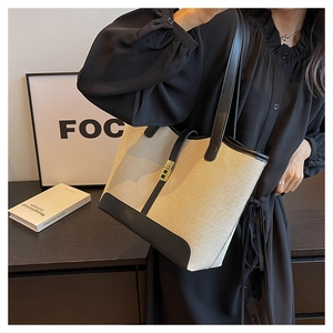 Detail view of large canvas tote bag with black leather trim and gold metal buckle