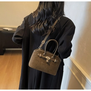 Vue détaillée du sac coquille en daim marron foncé avec boucle métallique sur un modèle