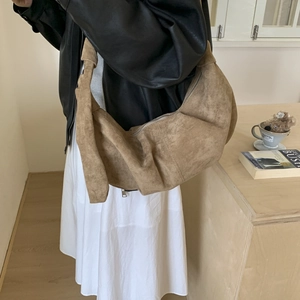 Close-up of brown suede hobo bag featuring knotted shoulder strap and silver zipper detail