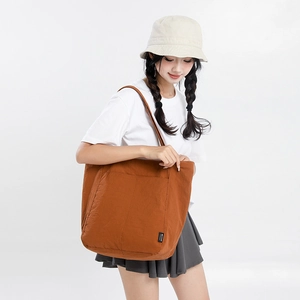 Gros plan détaillé d'un sac cabas en nylon marron avec poche et d'un chapeau bob beige